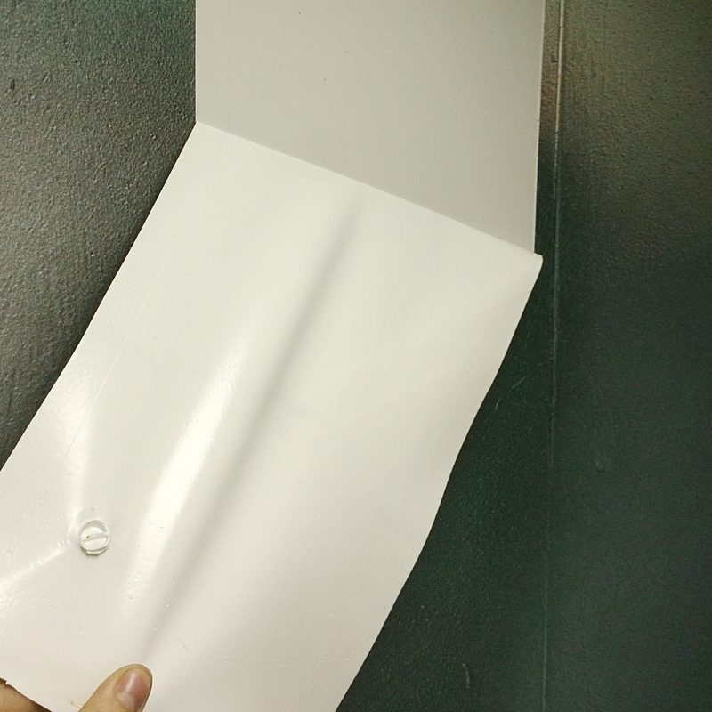 Getrockneter weißer Abziehlack löst sich als fester Film von der Wand