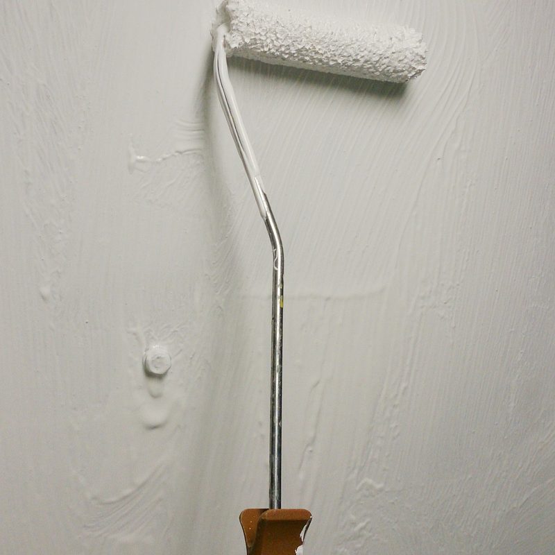 Weißer Abziehlack wird mit einer Lammfellrolle auf die Wand gerollt