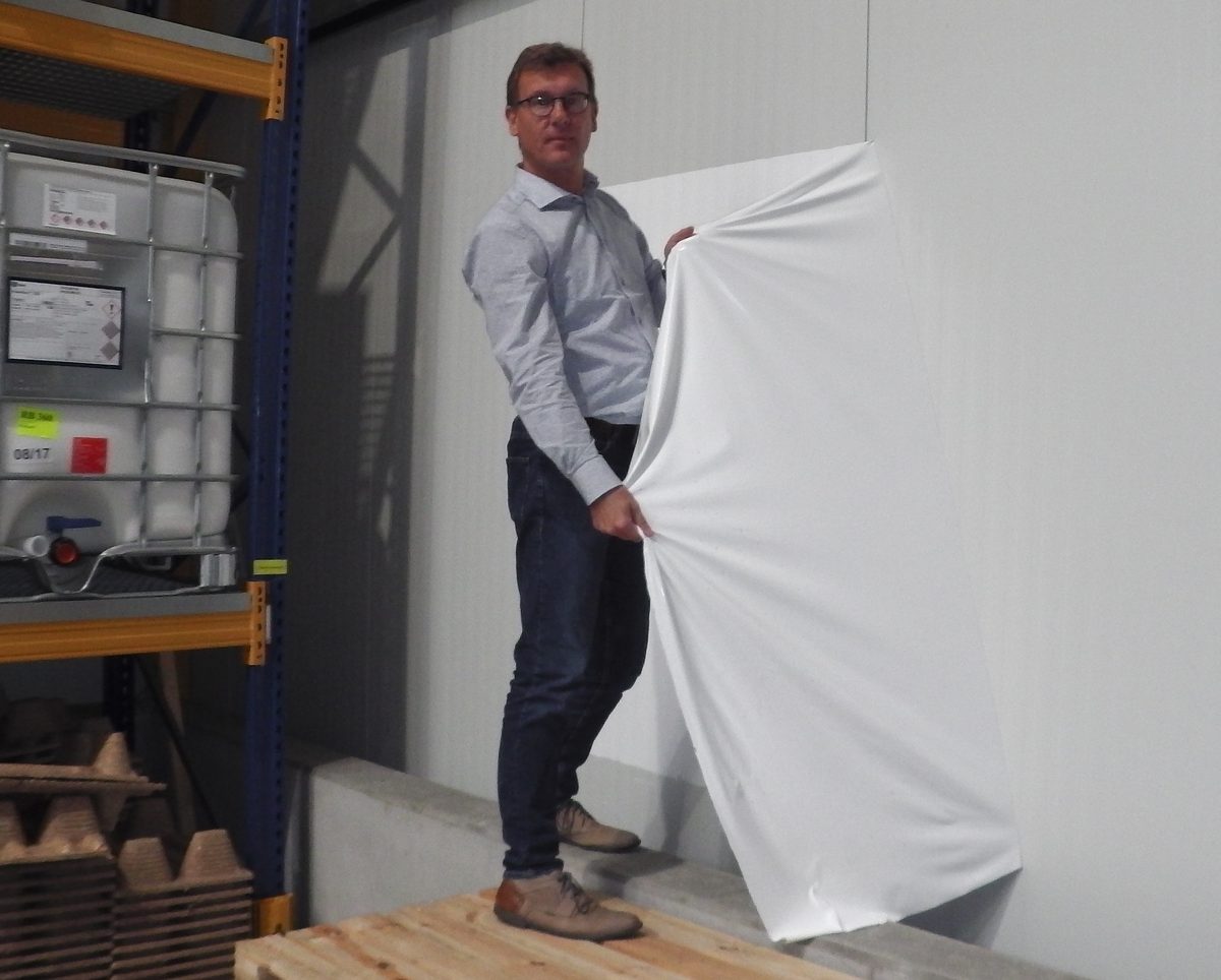 Weißer Abziehlack wird großflächig von einer Paneelwand abgezogen